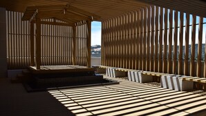 A sunlit room with a wooden slatted ceiling, a central seating area with a bench, and a view of a distant landscape. - Solis Hotel (Jinhu)