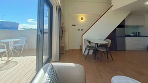 A modern interior with a balcony, a dining area with chairs, a staircase, and a kitchen. - Solis Hotel (Jinhu)