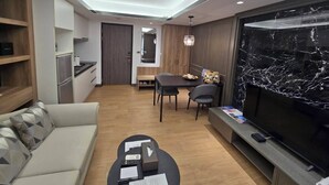 A modern living room with a sofa, coffee table, TV, and a dining area with a table and chairs. - Solis Hotel (Jinhu)