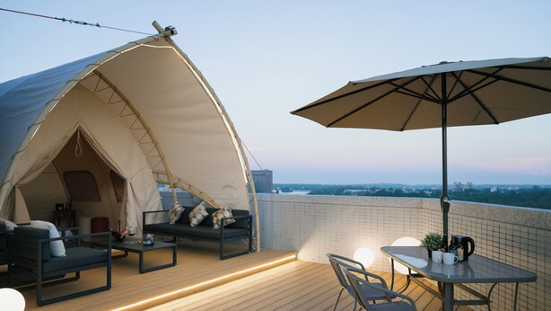 A rooftop terrace with a tent, seating area, and table with umbrella. - Solis Hotel (Jinhu)