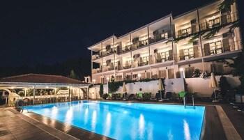 Un hotel de varios pisos con piscina, asientos al aire libre y balcones.