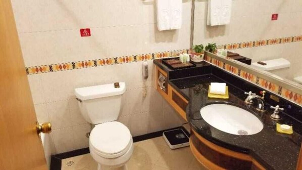 A compact bathroom with a toilet, sink, and mirror. - Panyu Guest House (Guangzhou)