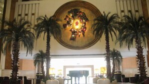 A lobby with a grand piano, palm trees, and a large decorative ceiling piece. - Panyu Guest House (Guangzhou)