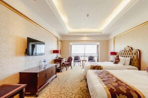 A hotel room with two beds, a TV, a desk, and a chair.