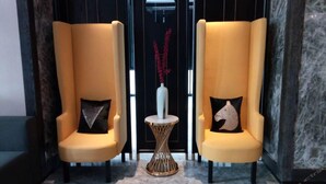 Two yellow armchairs with decorative pillows, a small round table with a vase, and a marble floor. - Paco Hotel (Shenzhen)