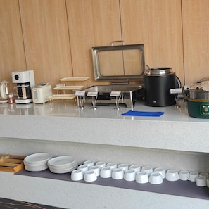 A kitchen area with a coffee maker, toaster, and a large pot on the counter. - Paco Hotel (Shenzhen)