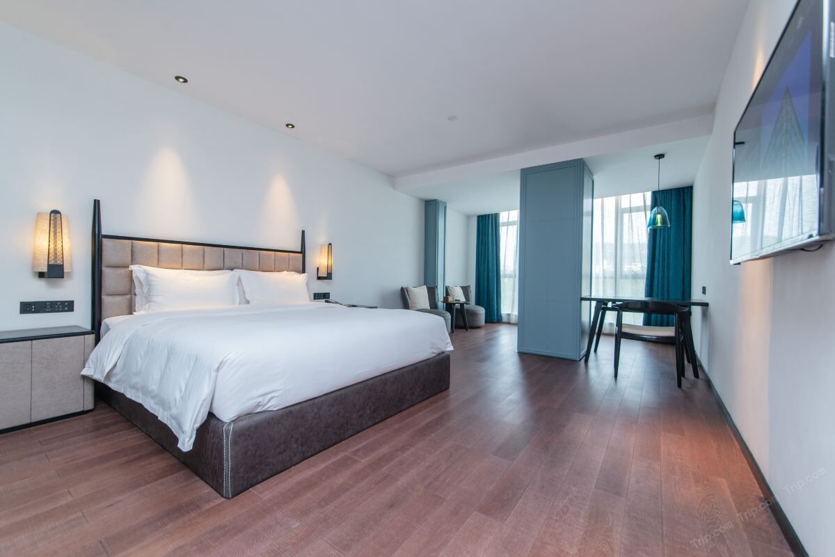 Et moderne hotelværelse med en stor seng, et skrivebord og et spiseområde.