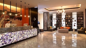 A modern lobby with a reception desk, seating area, and bookshelves. - Paco Hotel (Shenzhen)