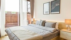 A bedroom with a bed, a nightstand, and two framed pictures on the wall. - Berkesy Residence (Shanghai)