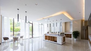 A modern hotel lobby with a central reception desk, large windows, and a polished floor. - Berkesy Residence (Shanghai)
