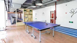 A ping pong table in a modern indoor space with a wooden floor, a bookshelf, and a wall-mounted bicycle symbol. - Berkesy Residence (Shanghai)