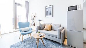 A modern living room with a grey sofa, a blue armchair, a small round coffee table, and a grey refrigerator. - Berkesy Residence (Shanghai)