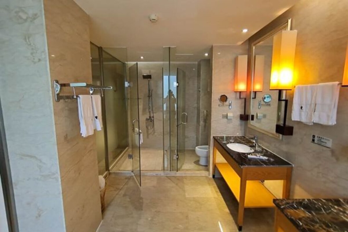 Une salle de bain moderne avec une douche à parois de verre, un lavabo en marbre et un grand miroir.