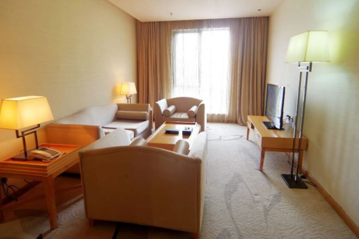 Une chambre d’hôtel équipée d’un canapé, d’un fauteuil, d’un bureau et d’une télévision.