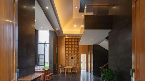 Un intérieur moderne avec un espace salon central, un escalier et un mur de bibliothèques.