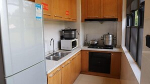 Une cuisine de taille réduite, dotée de meubles en bois, d’un réfrigérateur blanc, d’un four à micro-ondes, d’une cuisinière et d’un évier.