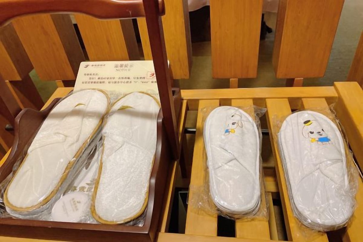 Una silla de madera con un par de pantuflas envueltas en plástico.