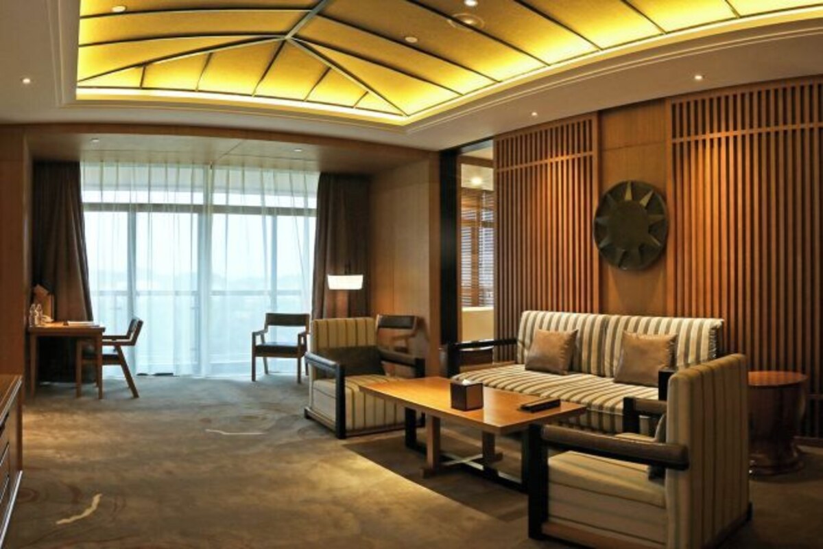 A modern hotel lobby with a sofa set, a coffee table, and a desk with chairs.