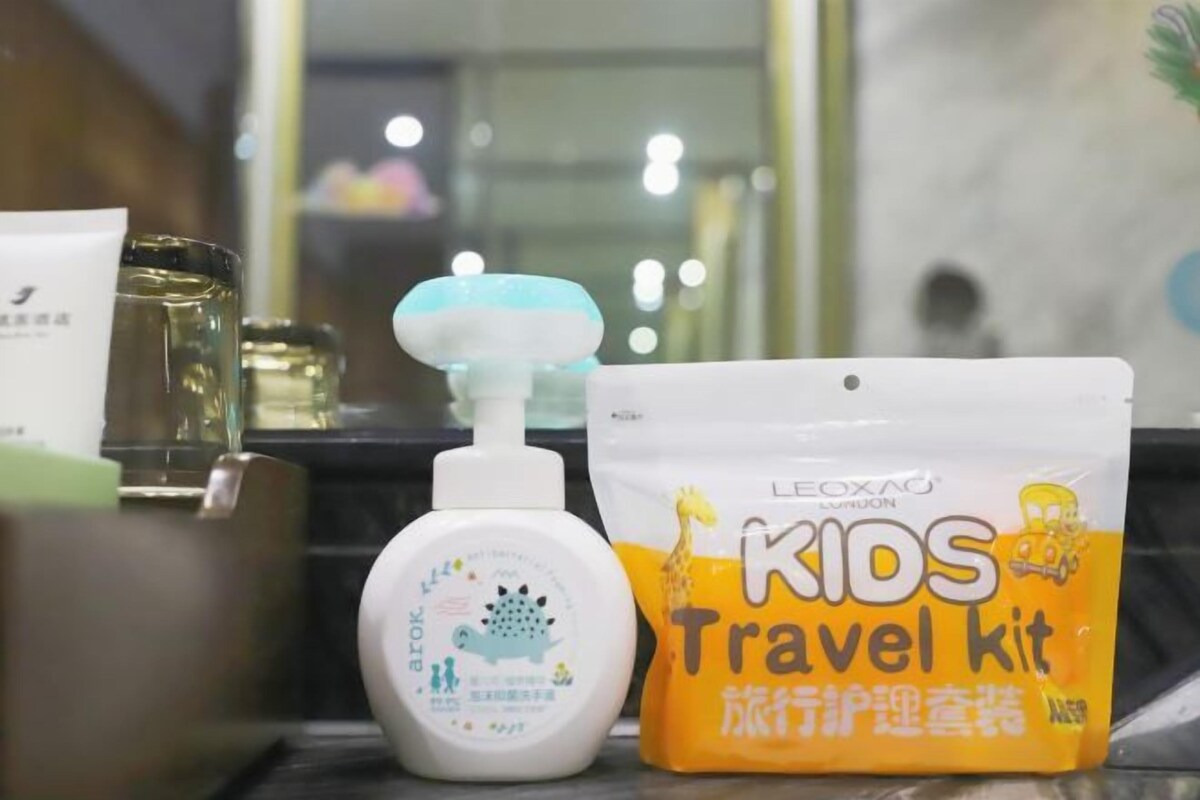 Un kit de viaje con diseño de jirafa, una botella de desinfectante de manos y una bolsita blanca.