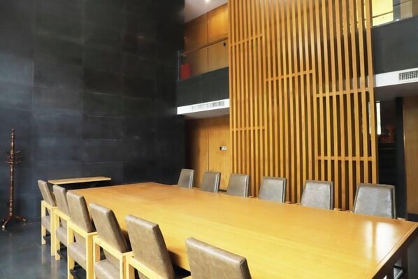 A conference room with a long wooden table and chairs, a black wall, and a wooden slat partition.