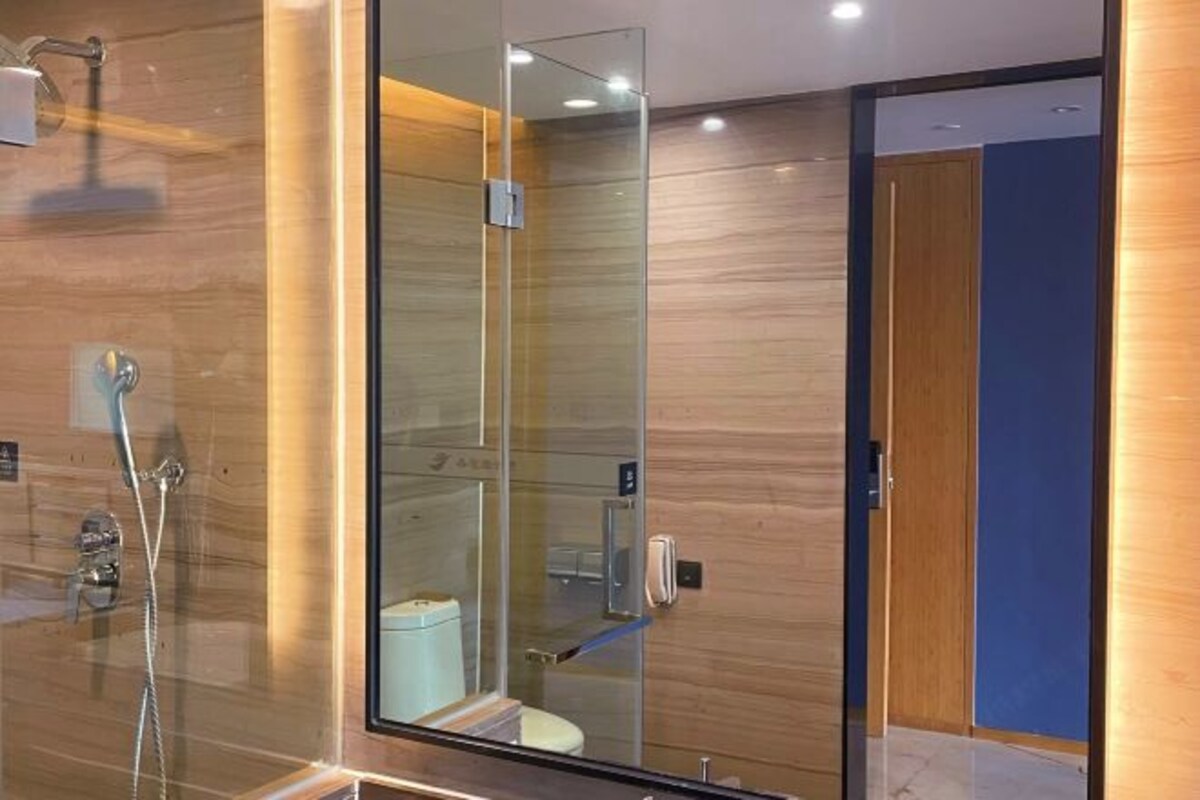 A modern bathroom with a glass shower enclosure, a visible toilet, and a wooden wall.