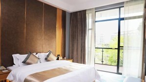 Une chambre d’hôtel avec un grand lit, une table de chevet, une fenêtre avec des rideaux et une vue sur l’extérieur.