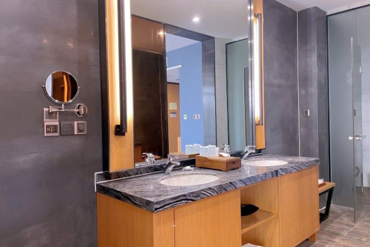 A modern bathroom with two sinks, wooden cabinets, and a large mirror.