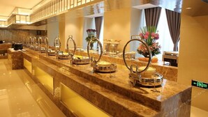 A buffet setup with various food stations, a marble counter, and a decorative vase with flowers. - Xingtai Yuehai Hotel (Haikou)