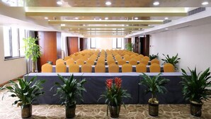 A conference room with rows of yellow chairs, a long table, and potted plants. - Xingtai Yuehai Hotel (Haikou)