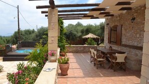 Un patio con piscina, mobiliario exterior y un muro de piedra.