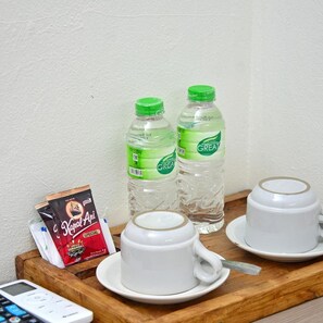 Un plateau avec deux tasses de café, deux bouteilles d’eau, un paquet de café et une télécommande.