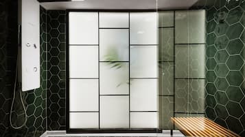 A modern bathroom with a shower, a glass partition, and a wooden bench.