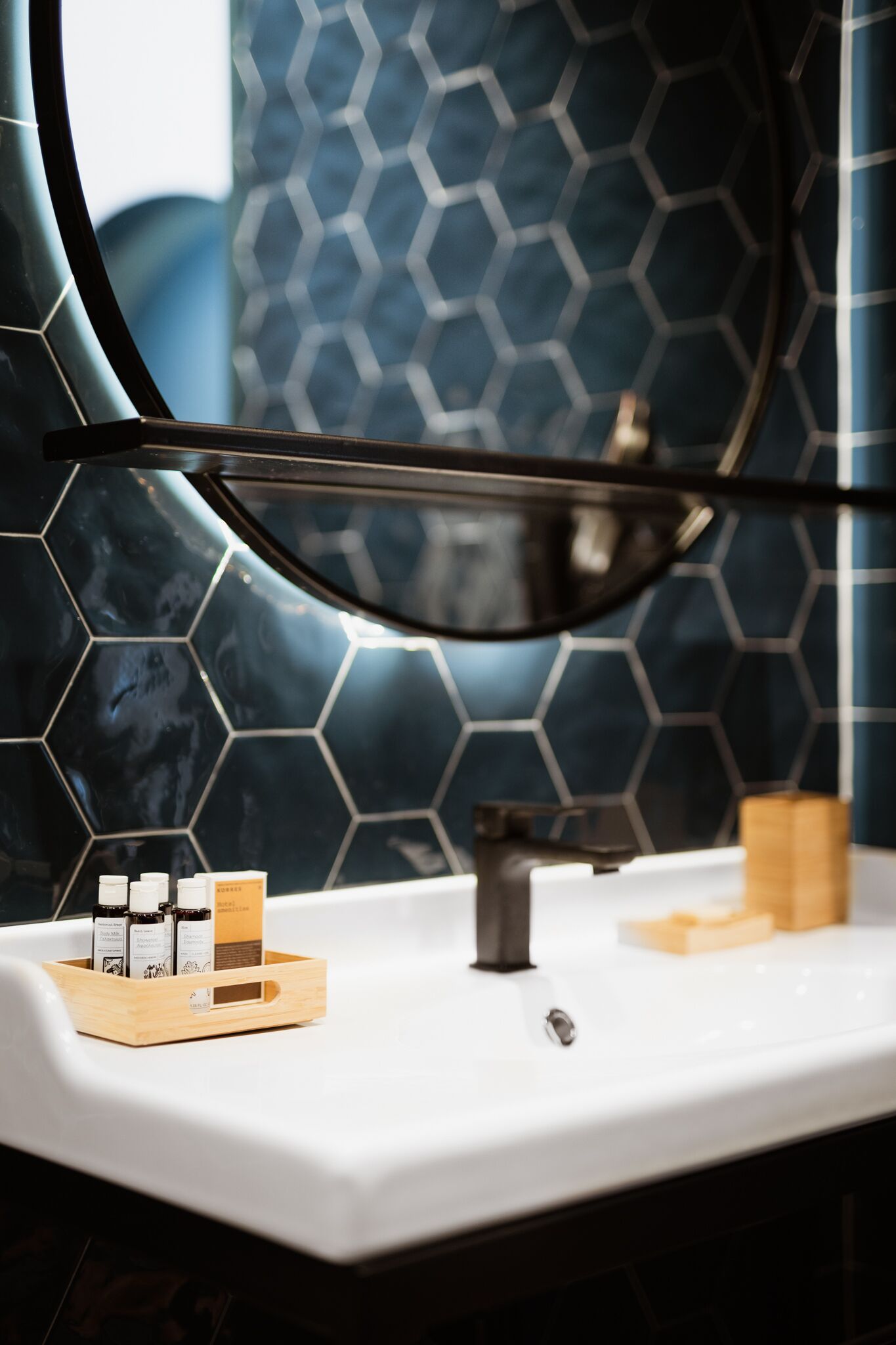 Un baño con un lavabo blanco, un espejo y un revestimiento de pared con patrón hexagonal.