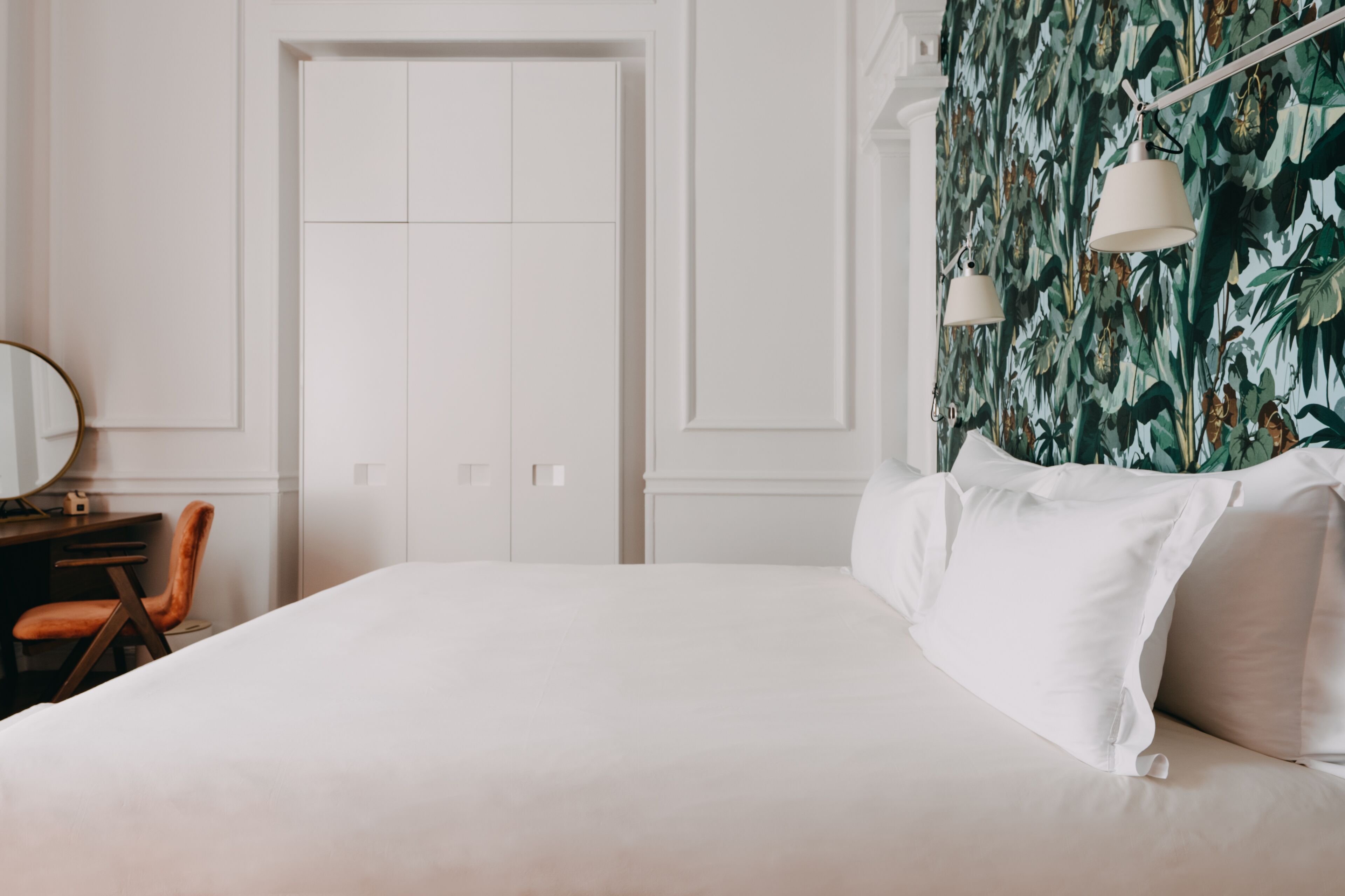 A bedroom with a large bed, a desk with a chair, and a wardrobe.
