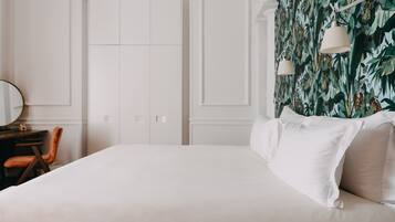 A bedroom with a large bed, a desk with a chair, and a wardrobe.