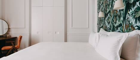 A bedroom with a large bed, a desk with a chair, and a wardrobe.