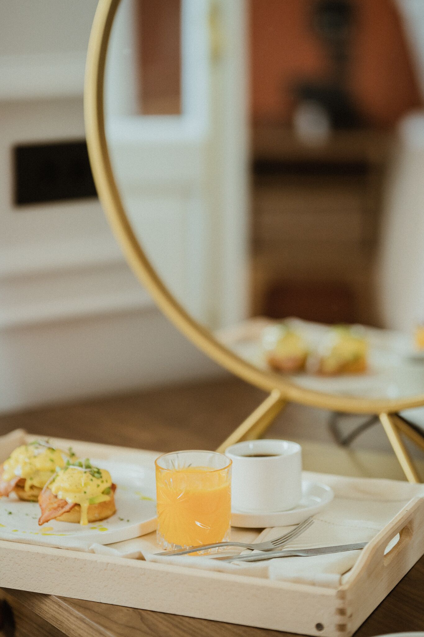 A breakfast tray with eggs benedict, a glass of orange juice, and a cup of coffee.