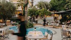 Un espace extérieur aménagé pour les repas, avec une piscine, entouré d’arbres et de tables avec des chaises.