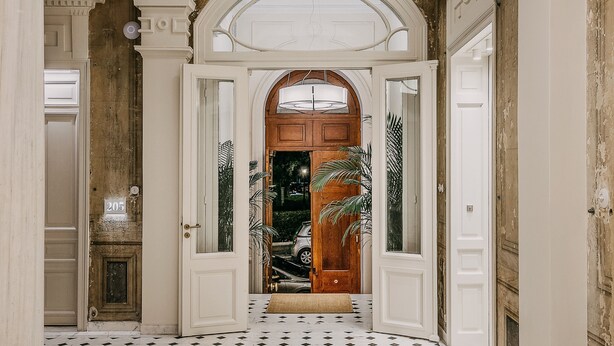 Un vaste hall d’entrée avec un plafond en arc de cercle, une porte en bois et un sol carrelé.