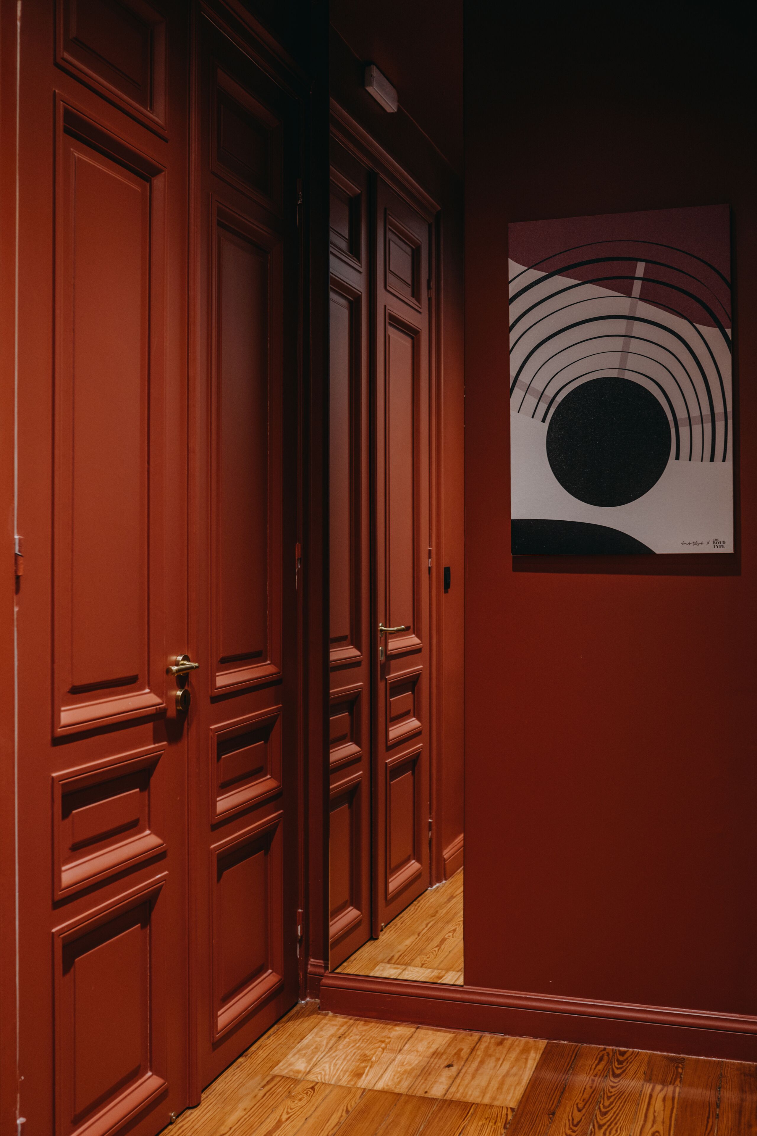 A hallway with wooden doors and a framed artwork on the wall.