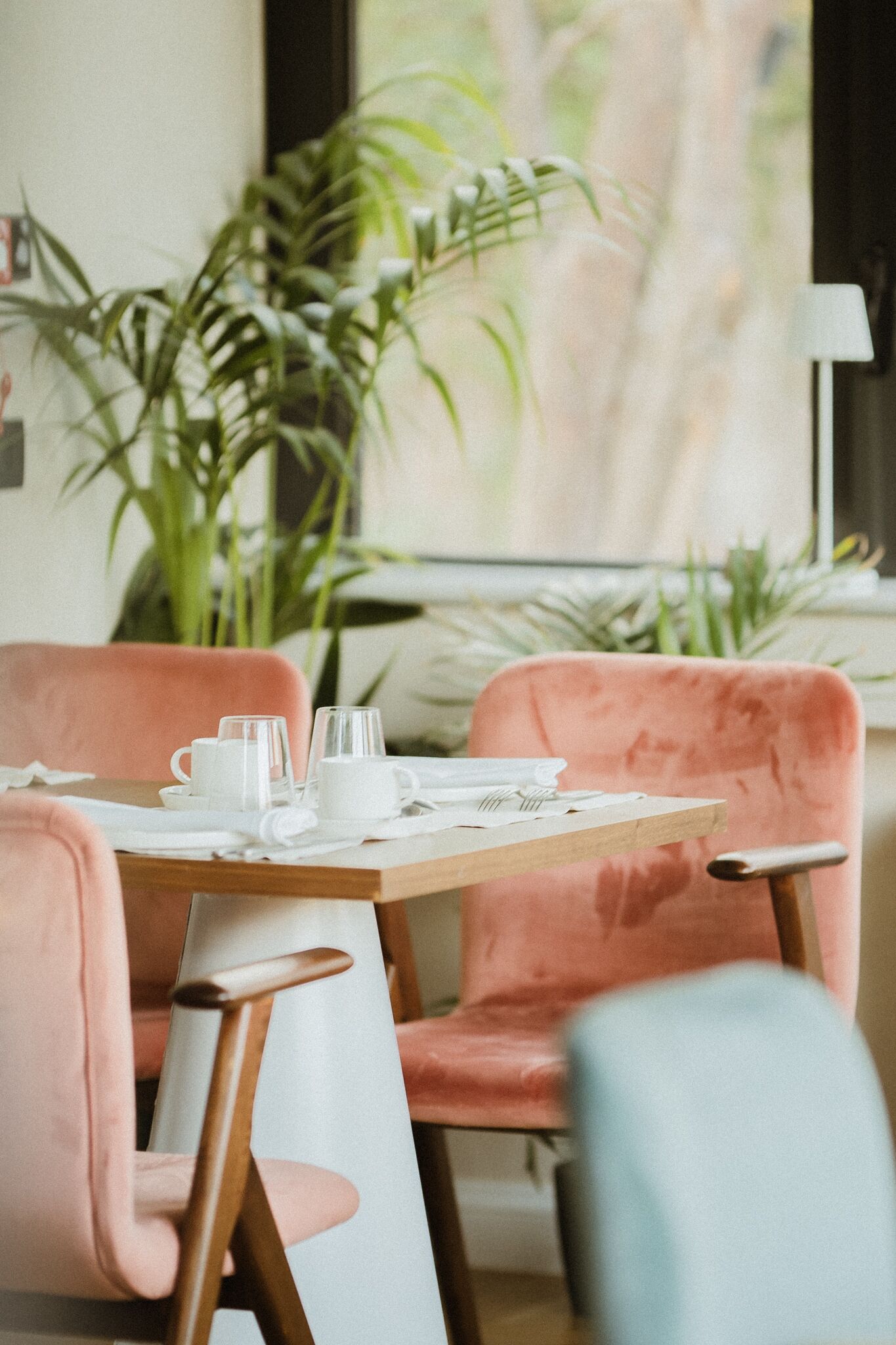 A dining area with a table set for two, featuring pink upholstered chairs and a glass top.