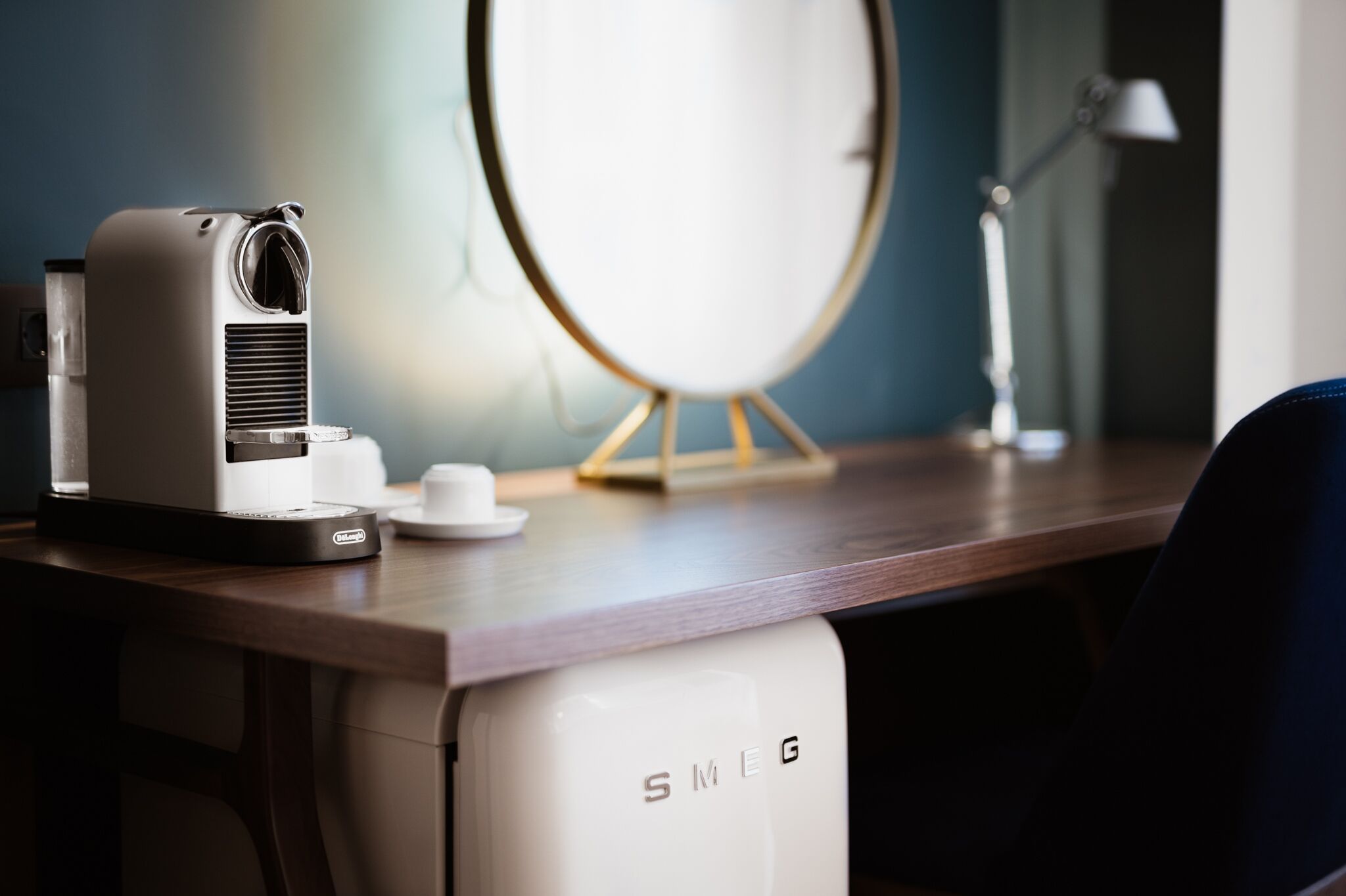 A desk with a white air purifier, a small white cup, and a round mirror on a wooden surface.