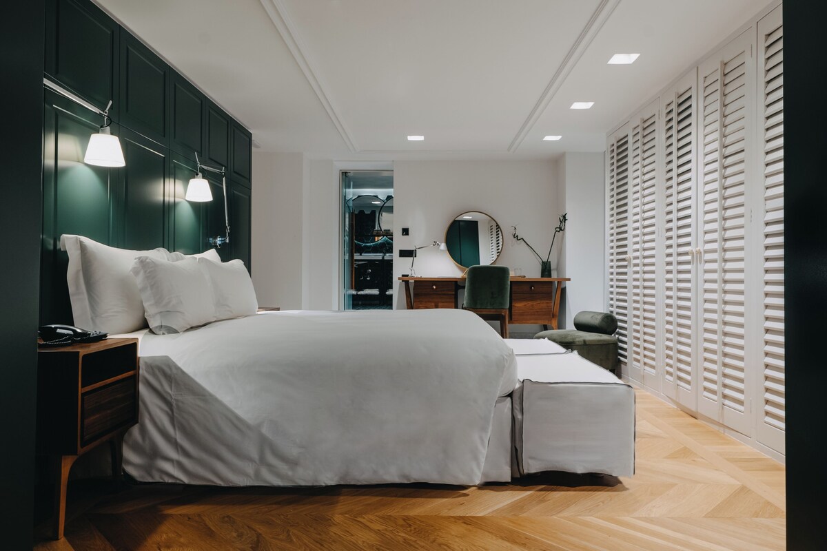 Ein modernes Schlafzimmer mit einem großen Bett, Nachttischen, einer Kommode und einem Spiegel.