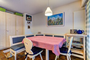 A dining area with a checkered tablecloth, wooden chairs, a hanging light fixture, and a painting on the wall. - Appartement Nevada 104 Spa - La Tzoumaz, 4 Vallees (La Tzoumaz)
