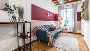 A modern living room with a teal sofa, a red accent wall, and a wooden ceiling. - Wine Apartments Florence Sangiovese (Florence)