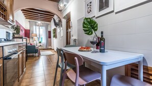 A modern kitchen with a dining table, chairs, and a wine bottle. - Wine Apartments Florence Sangiovese (Florence)