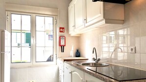 Una cocina moderna con armarios blancos, un lavamanos de acero inoxidable y una ventana con vistas al exterior.