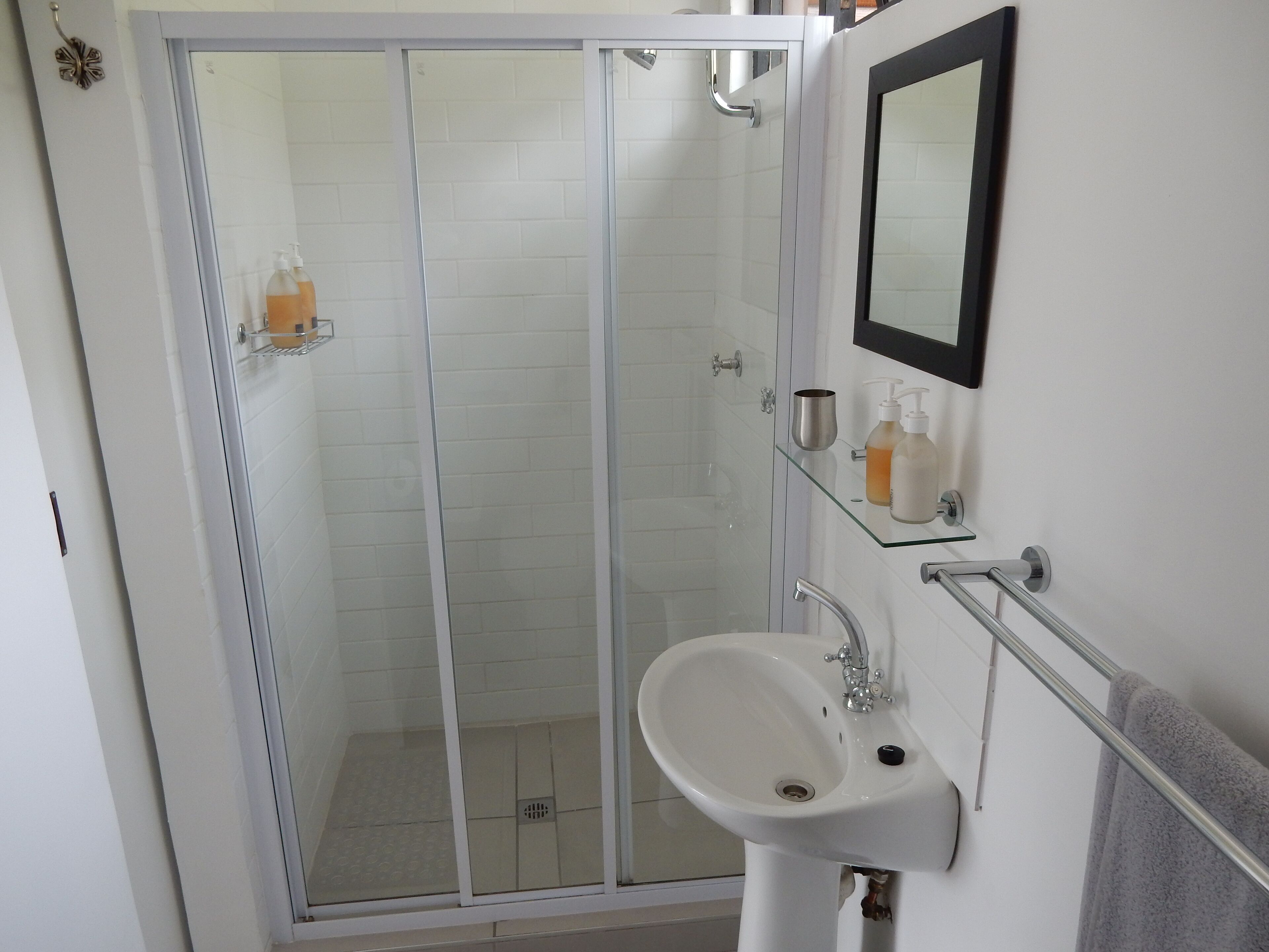 A bathroom with a glass-enclosed shower, a white sink, and a mirror above it.