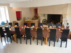 Comedor con una larga mesa dispuesta para una comida, rodeada de sillas.
