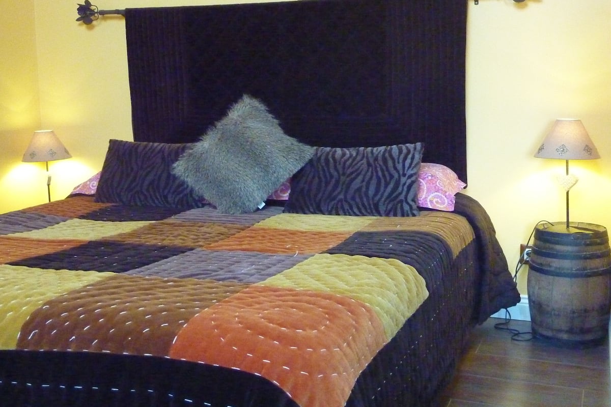A bed with a quilt, two lamps, and a decorative item on the wall.